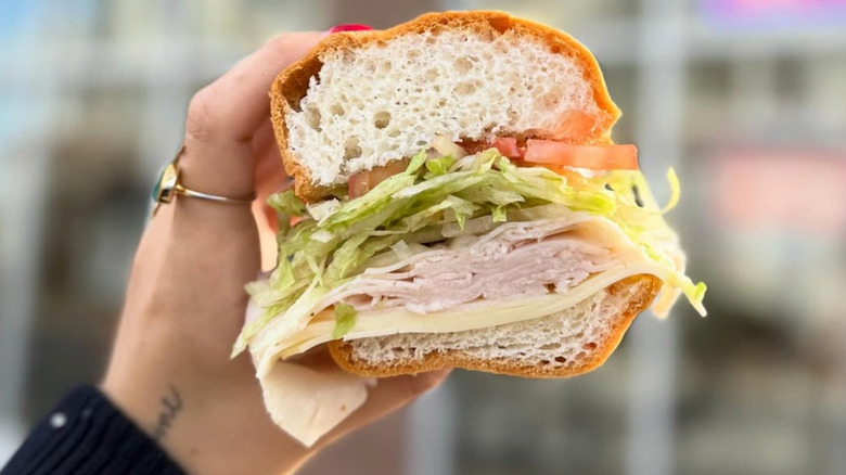 A hand holding up a gluten free turkey sub from Jersey Mike's