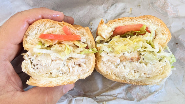 A hand holds a Jersey Mike chicken salad sub.