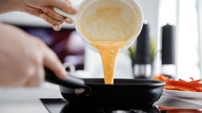 Pouring whisked egg into skillet