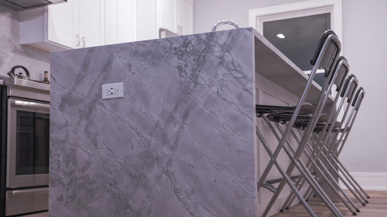 A kitchen island is made out of quartzite with diagonal streaks that follow the lines of the kitchen