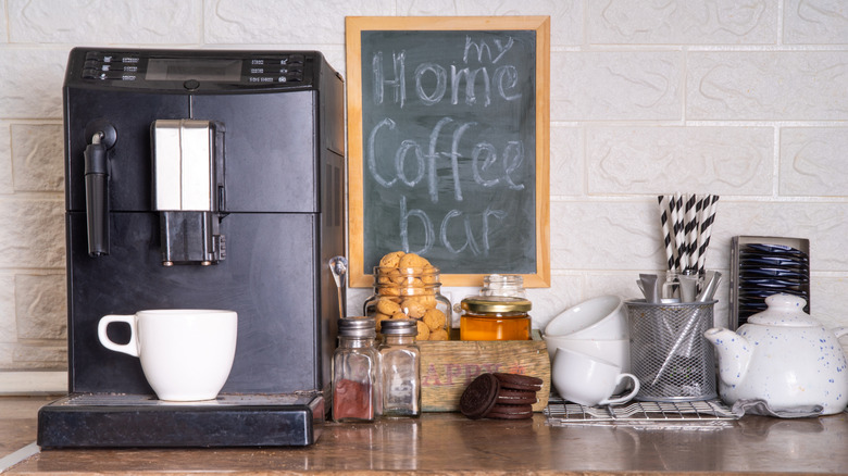 An in-home coffee station with an espresso machine, other items for making coffee, a teapot and teacups, a cookie jar, and a chalkboard