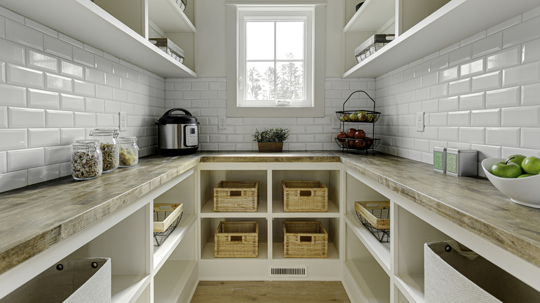 A butler's pantry with white subway tile, a window, and a light-colored countertop