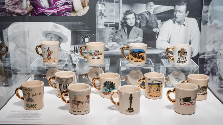 A glass case contains John Wayne gold handle mugs.