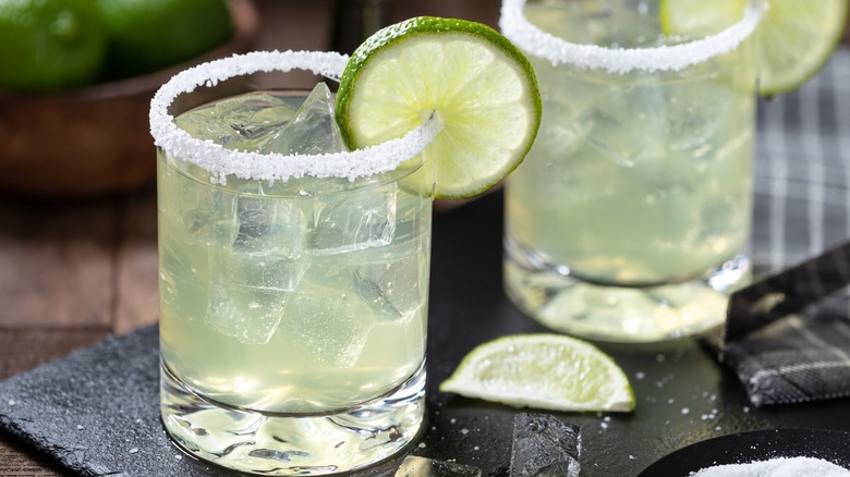 Two margaritas with lime wheels and sugar rim