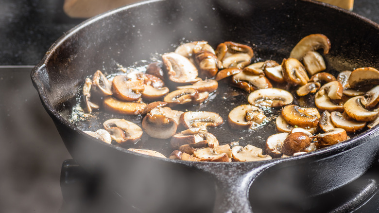 Mushrooms being sauteed in a cast-iron pan