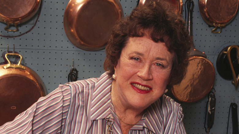 Chef Julia Child in front of a wall of copper pans.