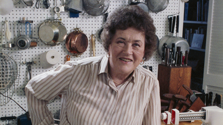 Julia Child smiling in front of pots and pans