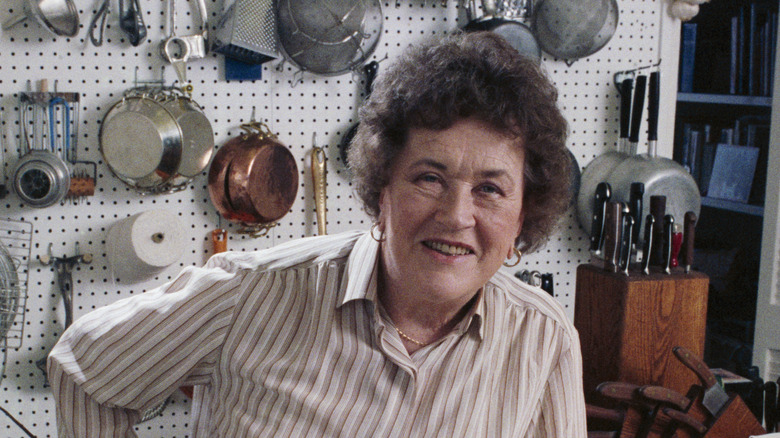 Julia Child in kitchen surrounded by cooking tools