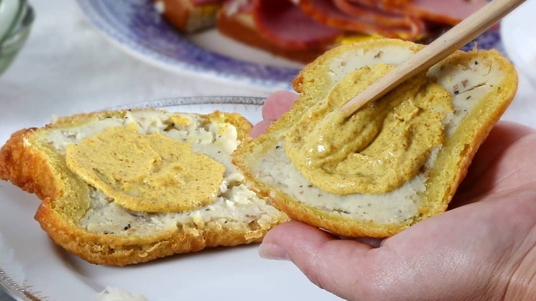 Someone spreads mustard on a Coney Island knish from Gabila's.