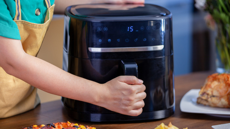 Woman hand on handle of an air fryer
