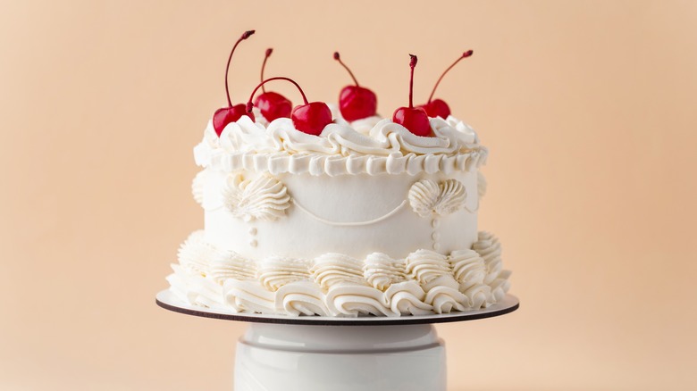 Fully frosted white birthday cake with cherries on top