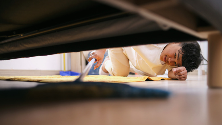 Man cleaning under an appliance with a retractable tool