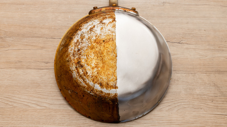 A pan that has baked-on food on one side, and is clean on the other