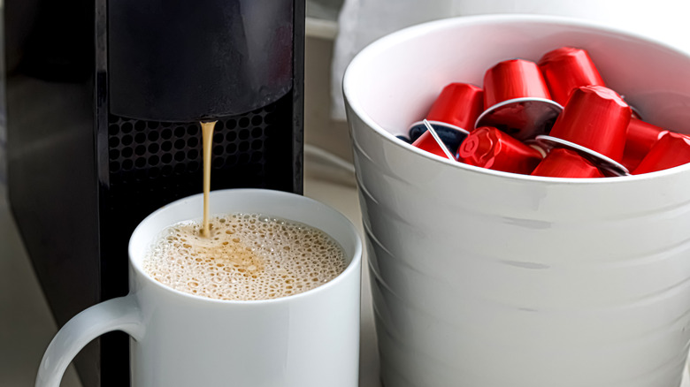 Coffee machine brewing next to capsules.