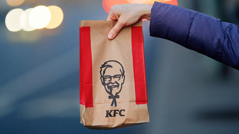 A hand holds a KFC bag.