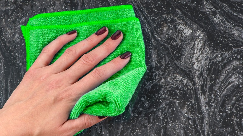 A hand cleaning marble countertop with microfiber cloth