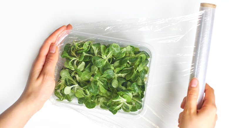 Cling film over greens in container