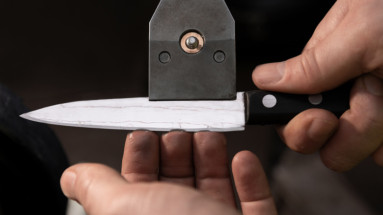 Closeup of hands checking a knife edge for burrs
