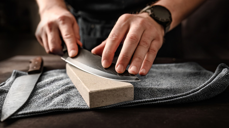 Closeup of a person sharpening a chef knife on a whetstone