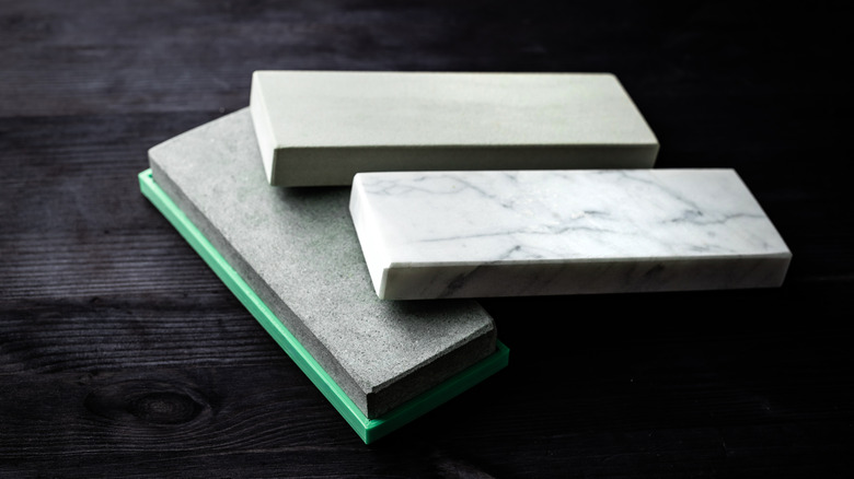 Different grains of whetstones are piled on a dark colored table