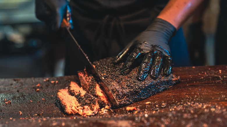 A barbecue grill master cutting up smoked brisket