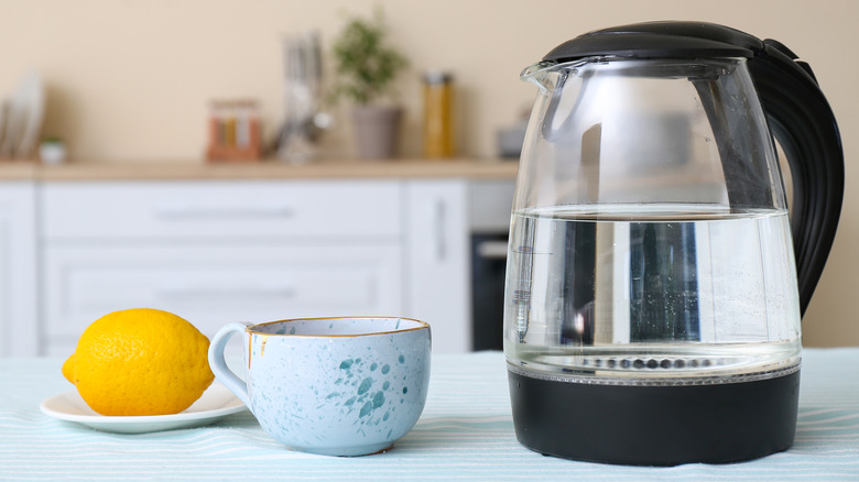 Kettle of water next to cup and lemon