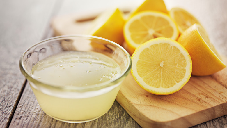 Bowl of lemon juice next to cut fruit