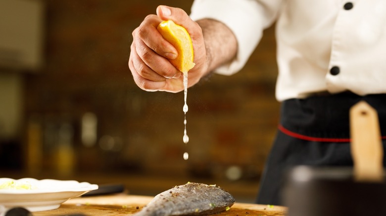 Squeezing lemon on fish
