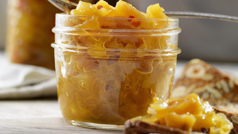 Pineapple chutney in a jar with a spoon on top