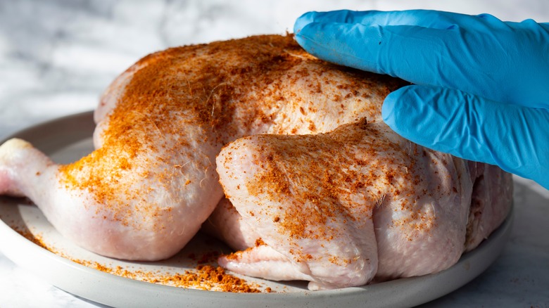 person dry rubbing raw chicken