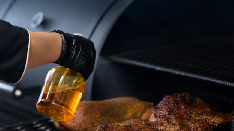 person baste spraying barbeque meat