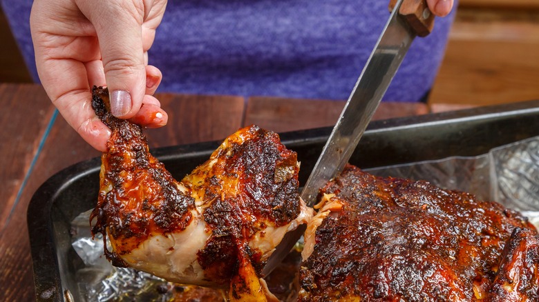woman cutting chicken leg