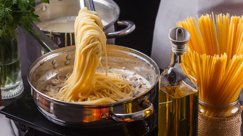 Cook dropping spaghetti into a sauce