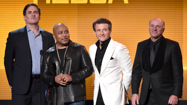 Select members of the Shark Tank cast (Cuban, John, Herjavec, and O'Leary) standing and giving an award