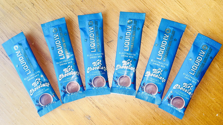 Six packets of Liquid I.V. Hydration Multiplier Hot Chocolate fanned out on wooden table