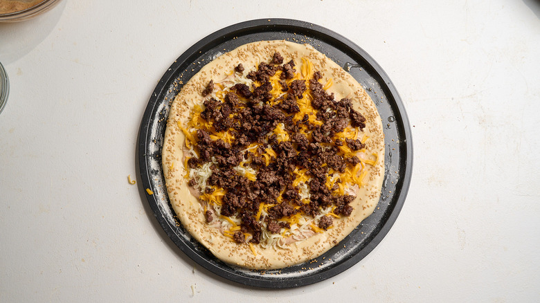 crumbled beef added to pizza dough