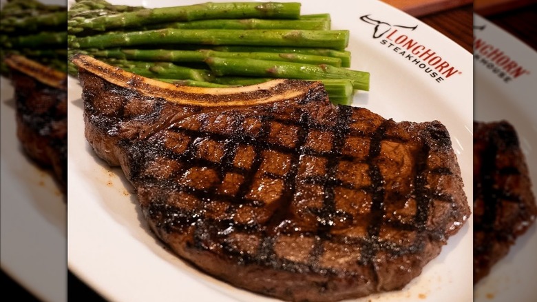 LongHorn outlaw ribeye on a plate with some asparagus.