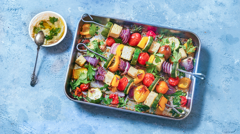 Variety of colorful roasted vegetable skewers on a baking tray
