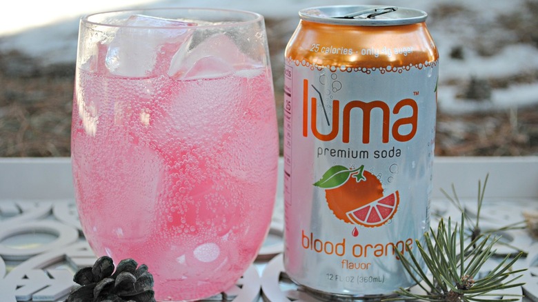 glass of blood orange luma soda and can of it