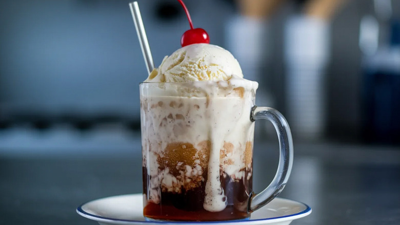 Root beer float served in a glass, topped with a cherry.