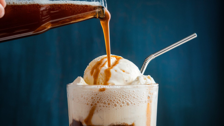 Pouring root beer over vanilla ice cream.