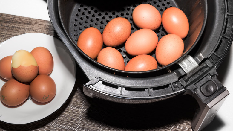Hard-boiled eggs in air fryer basket and on white plate