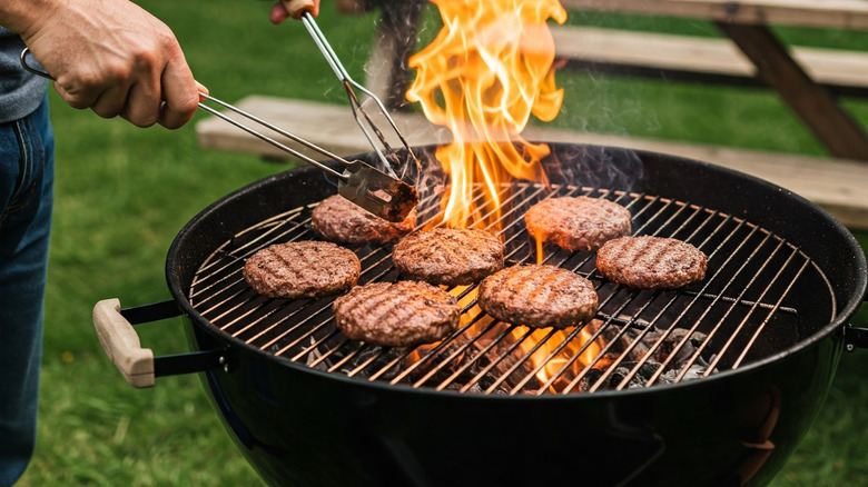 Someone grills burger patties outdoors.