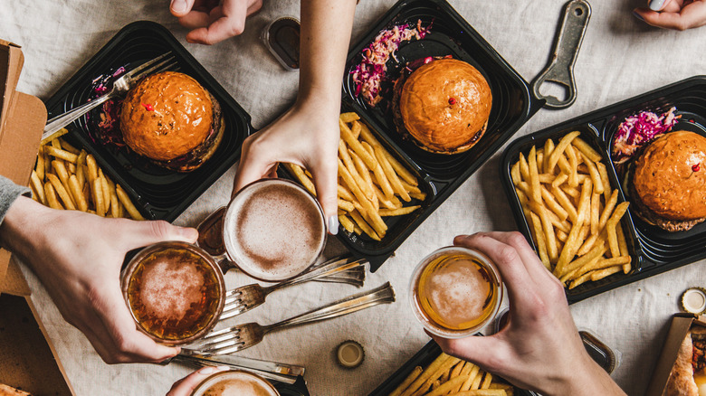 clinking glasses over burgers and fries