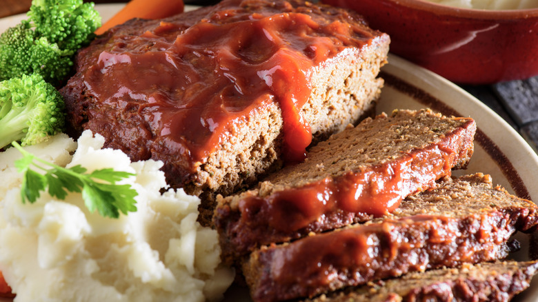Sliced meatloaf served with veggies.