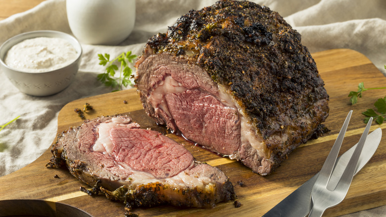 One slice is taken out of a standing prime rib roast