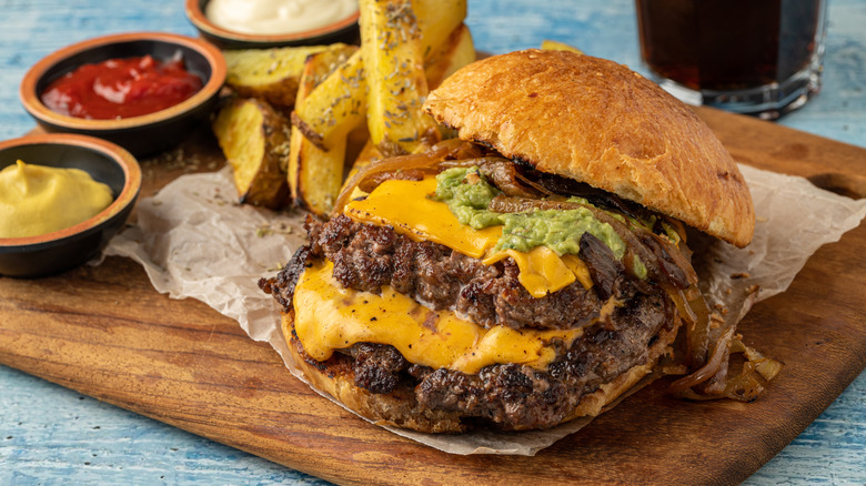 A fully-loaded smash burger on a wooden board