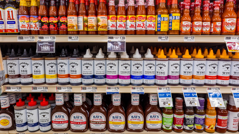 A selection of barbecue sauces on a shelf in a store.