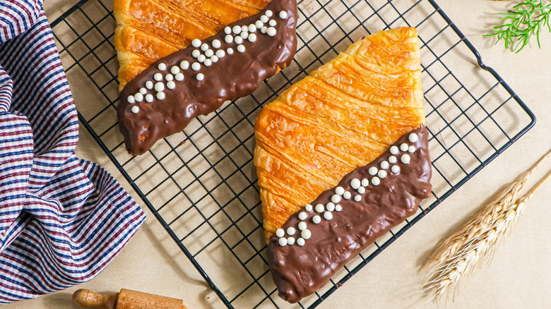 Flattened croissants with a layer of chocolate icing on one side.