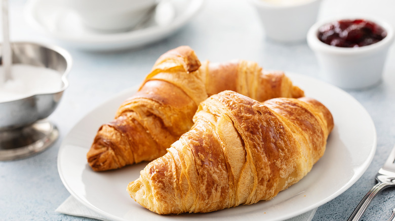 Croissants on a white plate with jam in the background